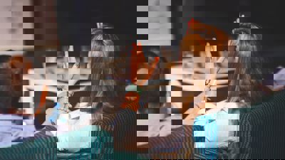 A woman holding her hands up while sitting down at an event - Image taken from behind