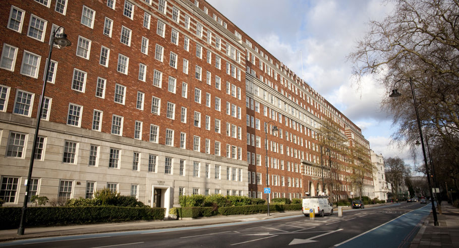 A wide shot of a brown apartment complex from the other side of the street