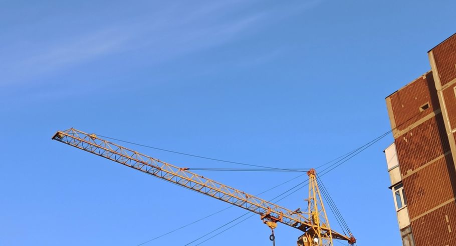 A crane over apartment blocks under construction during golden hour