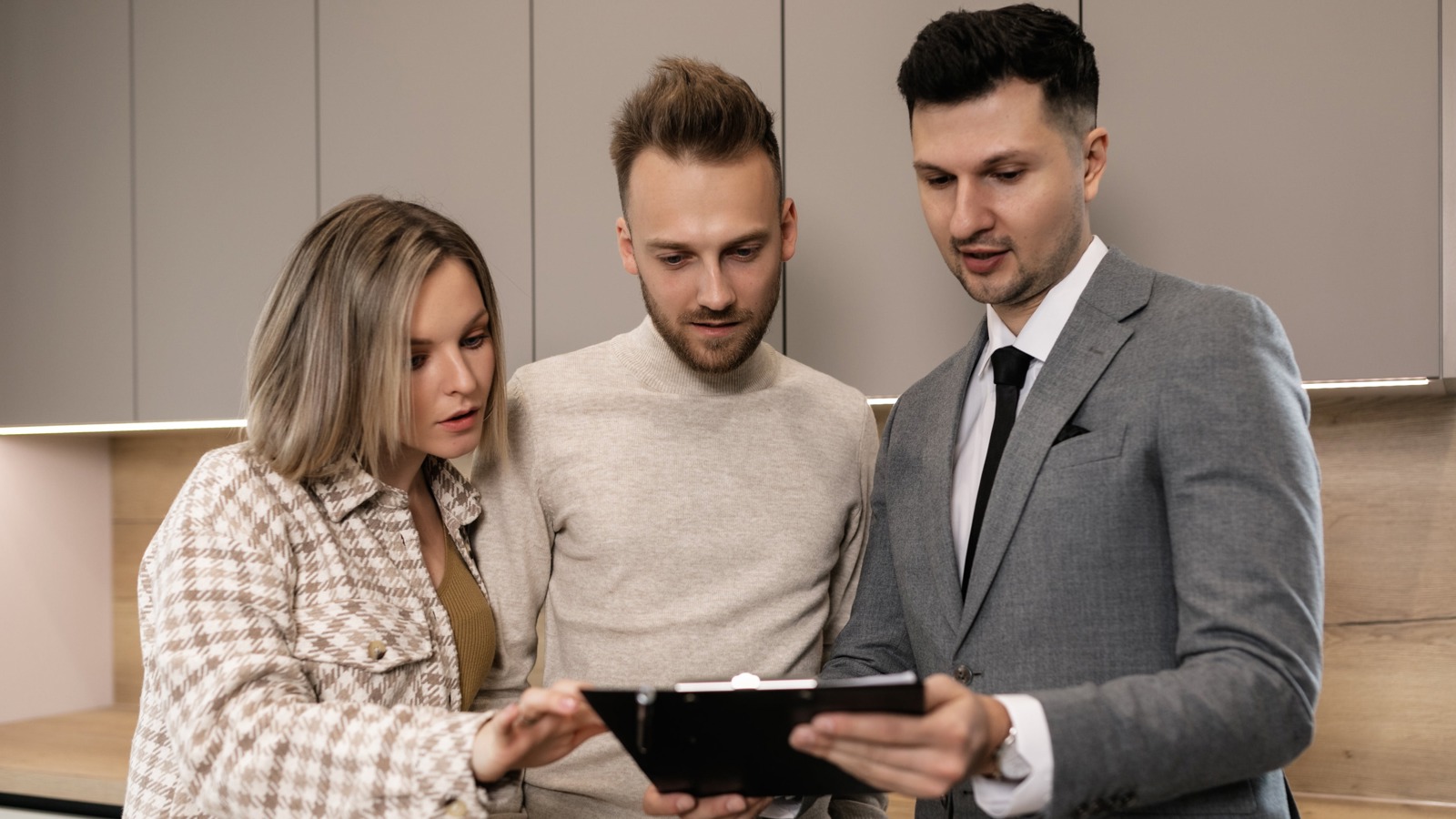A property manager showing documents on a clipboard to a couple